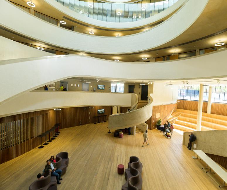 A modern building with curved staircases and curved glass internal and external windows.