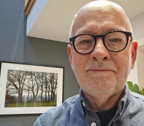 Man stood in front of a picture of trees