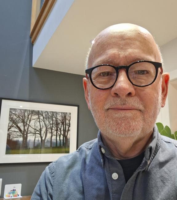 Man stood in front of a picture of trees